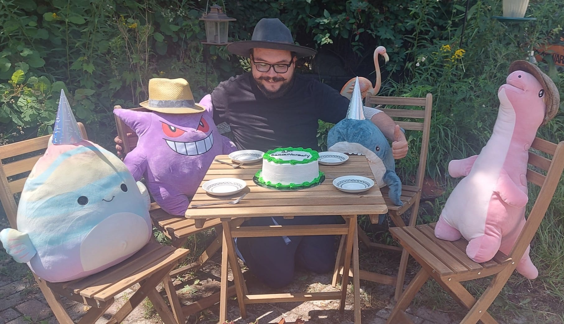 A man with facial hair and a felt sun hat has joined stuffed animal patio party, Photo 3